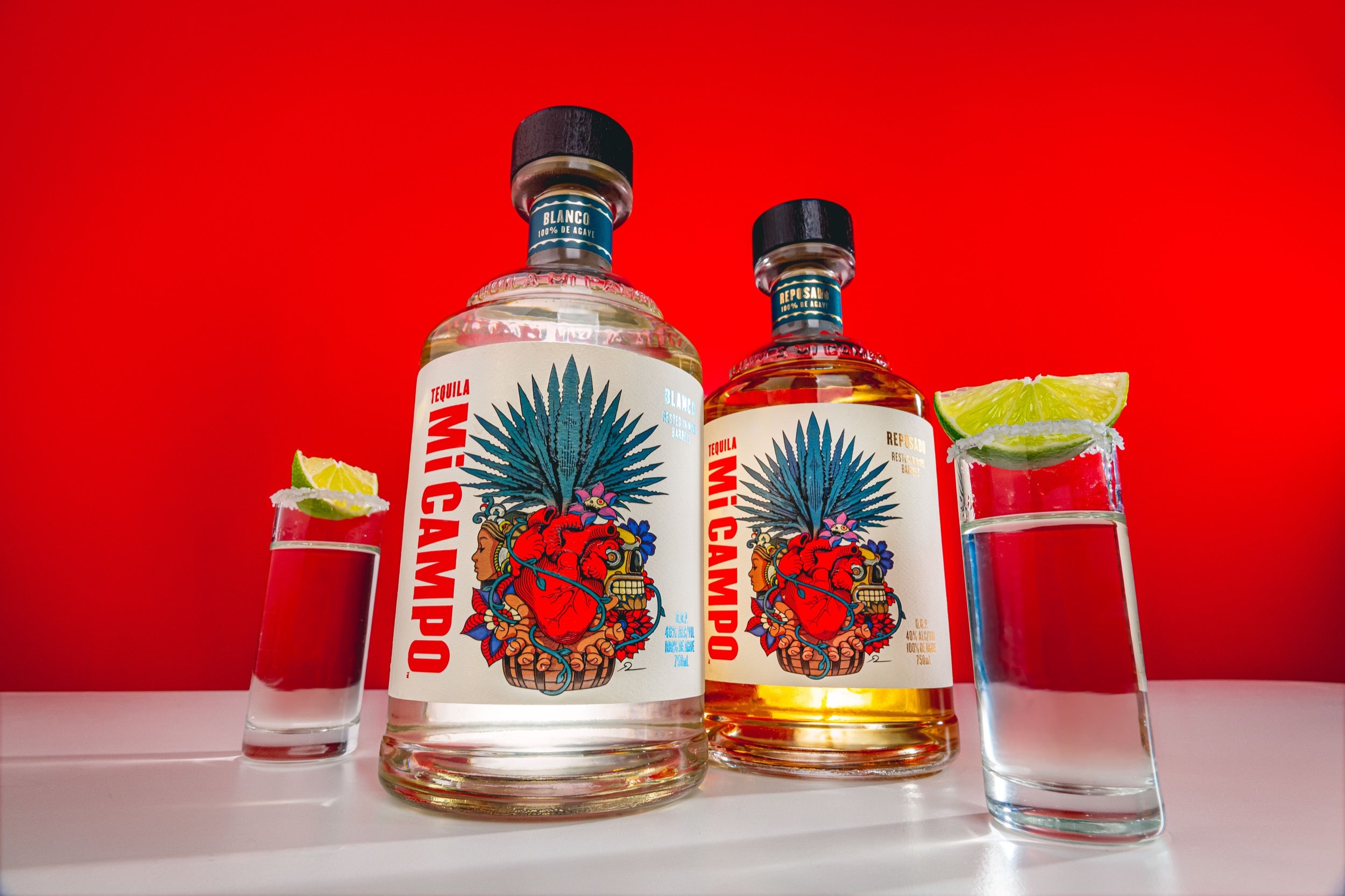 Two bottles of Mi Campo tequila with glasses and limes