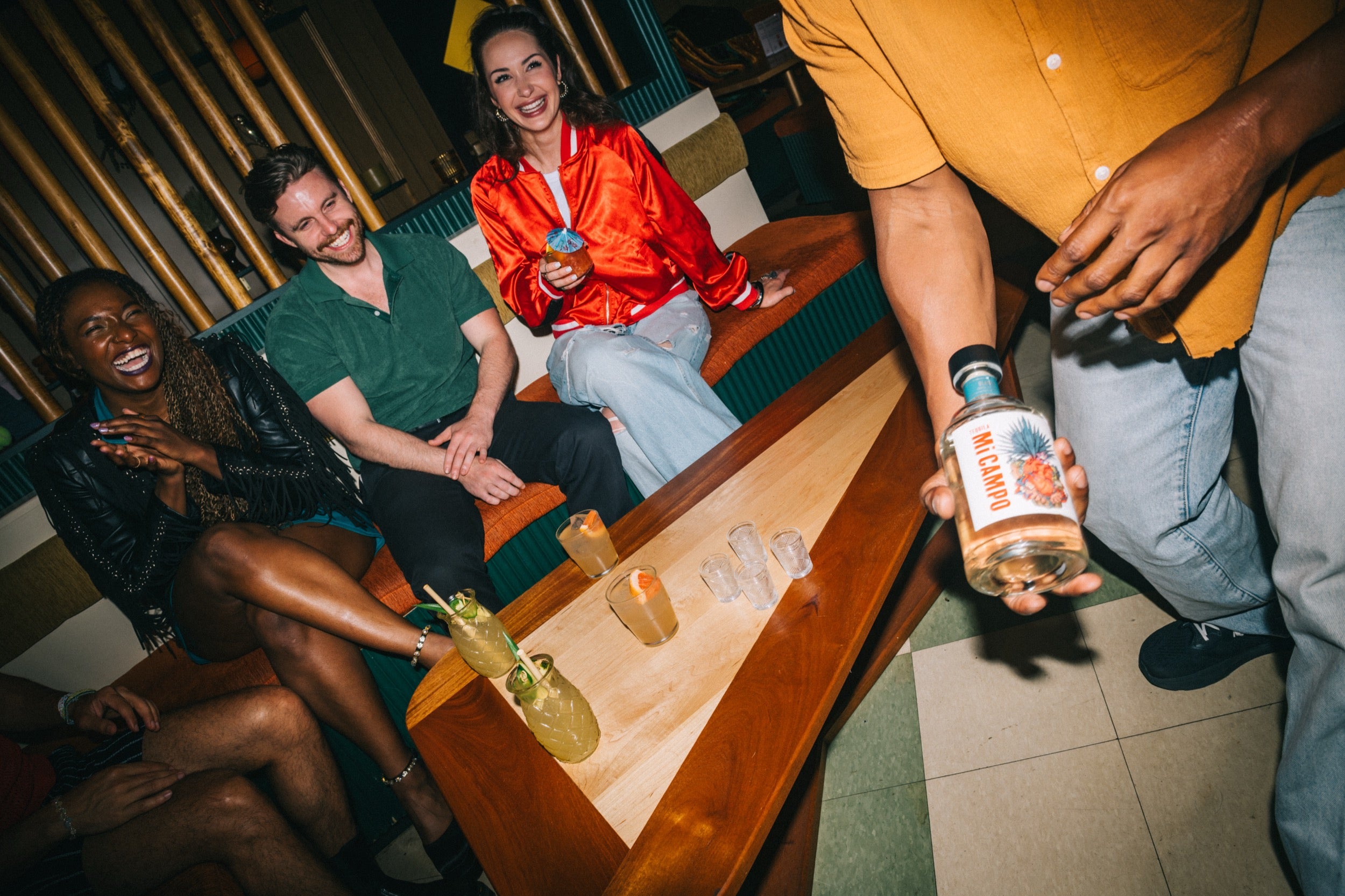 People sitting around a wooden table with drinks in a casual setting