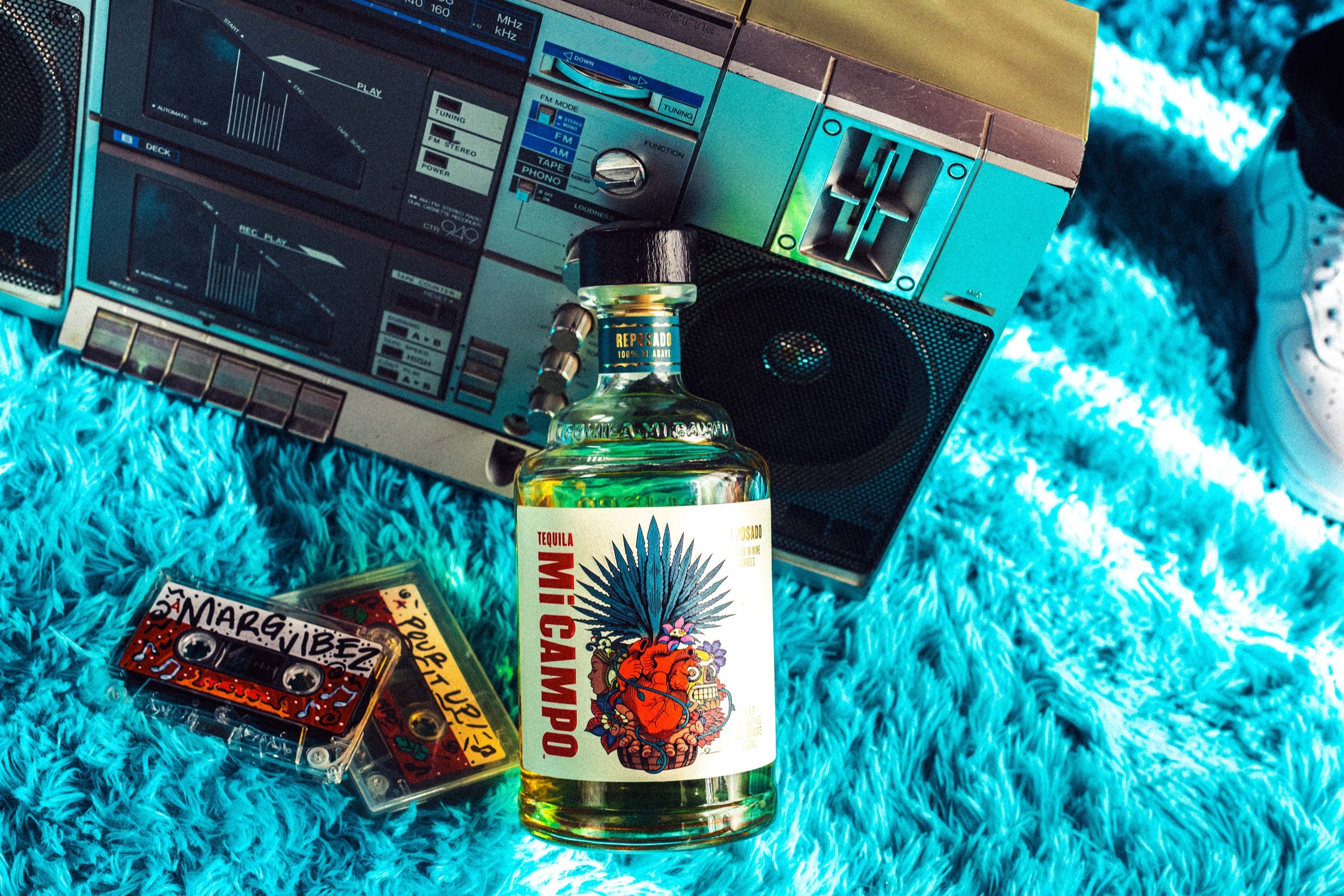 Bottle of Mi Campoi sitting in front of vintage boom box with a mixtape named "marg vibes" laying next to it.