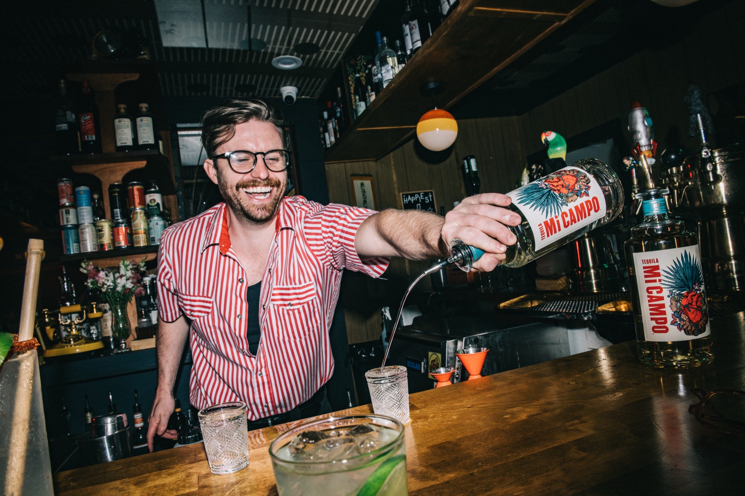 Barista pouring a drink from MI Campo bottle into a glass at a bar.
