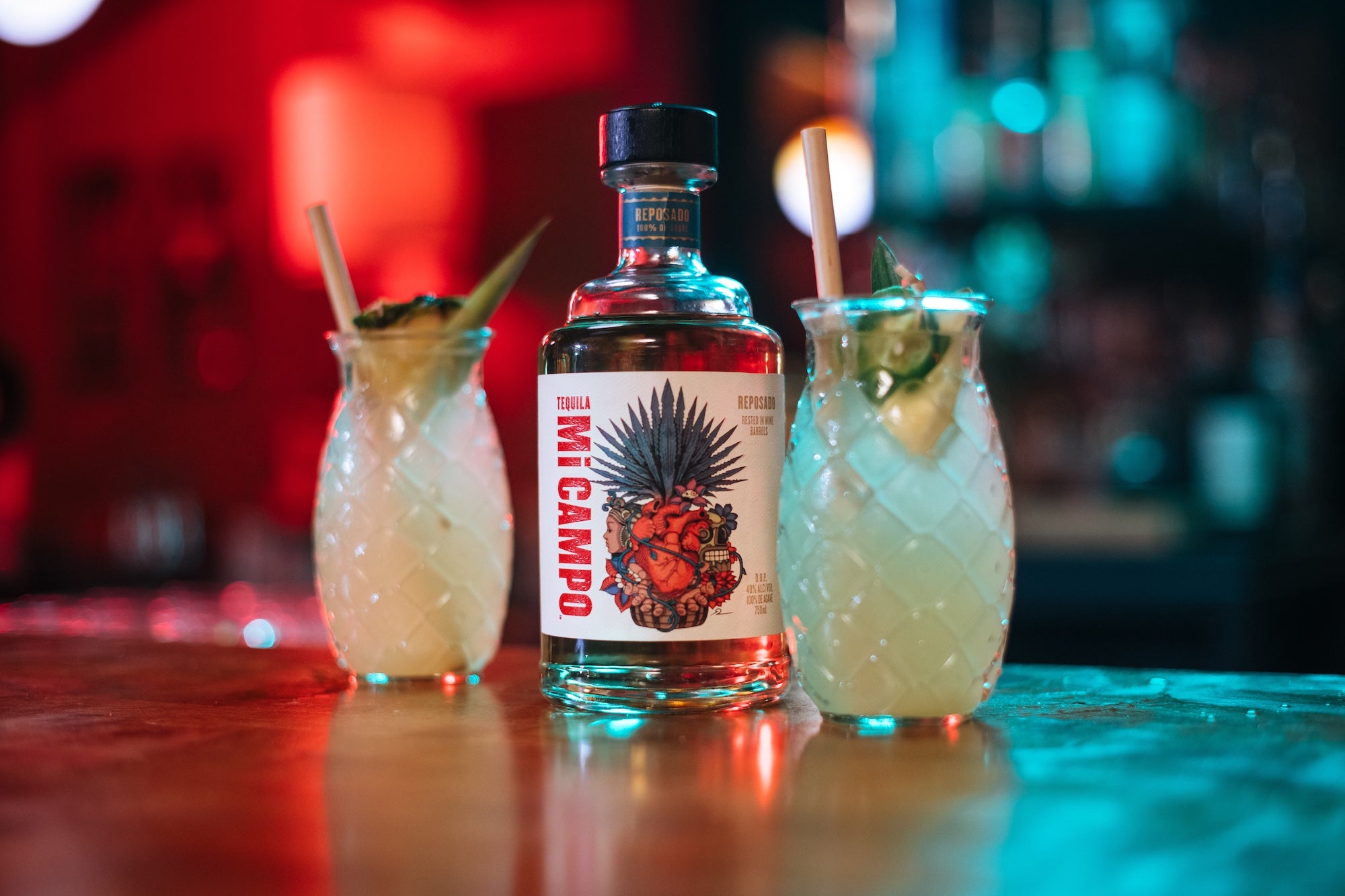 Bottle of Mi Campo with two cocktails on a bar counter