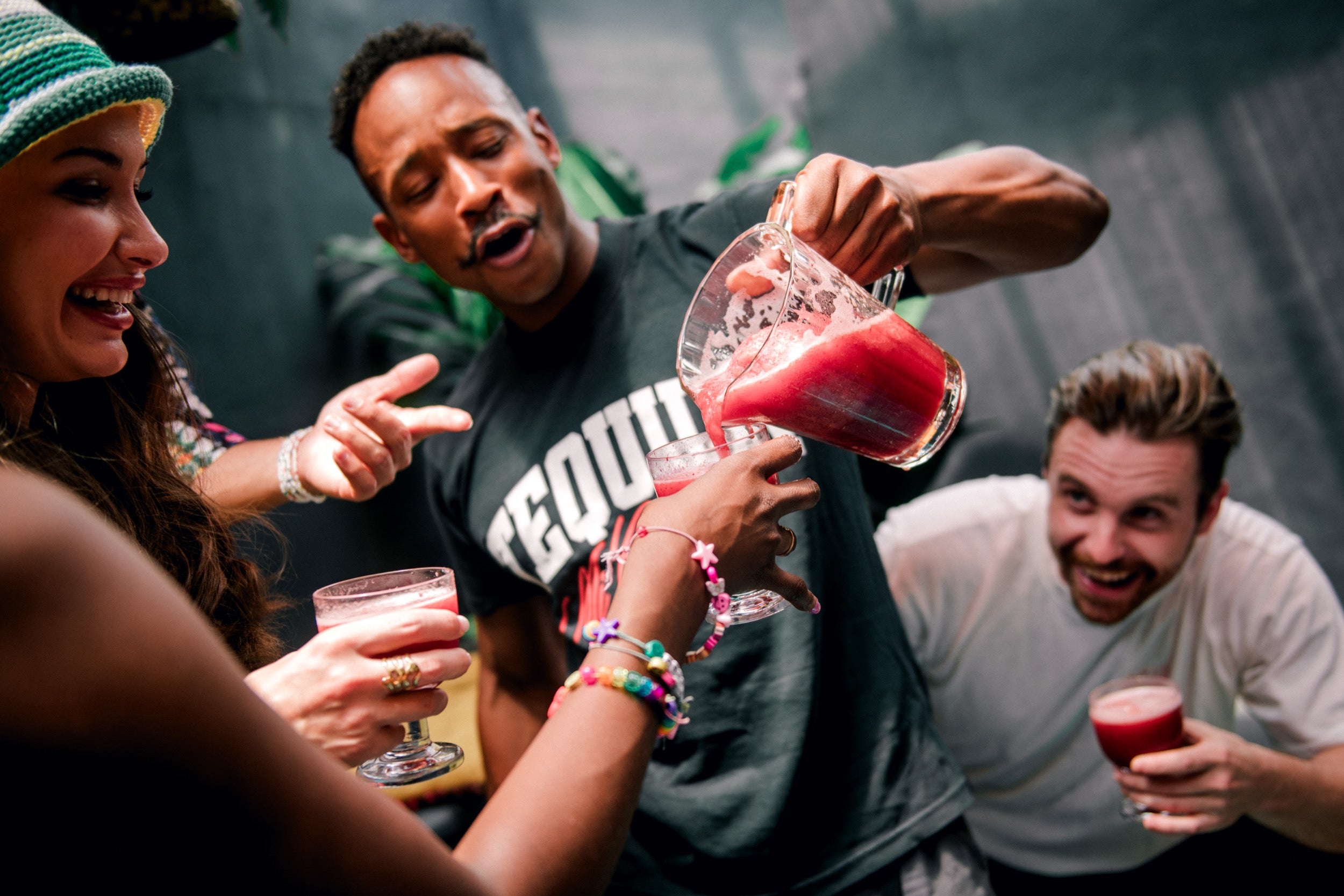 People enjoying drinks together with a focus on a person pouring a red drink.