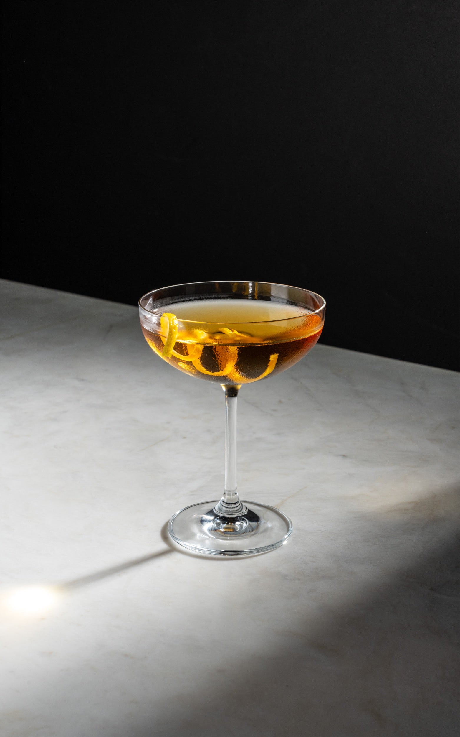 Cocktail in a glass on a reflective surface with a dark background
